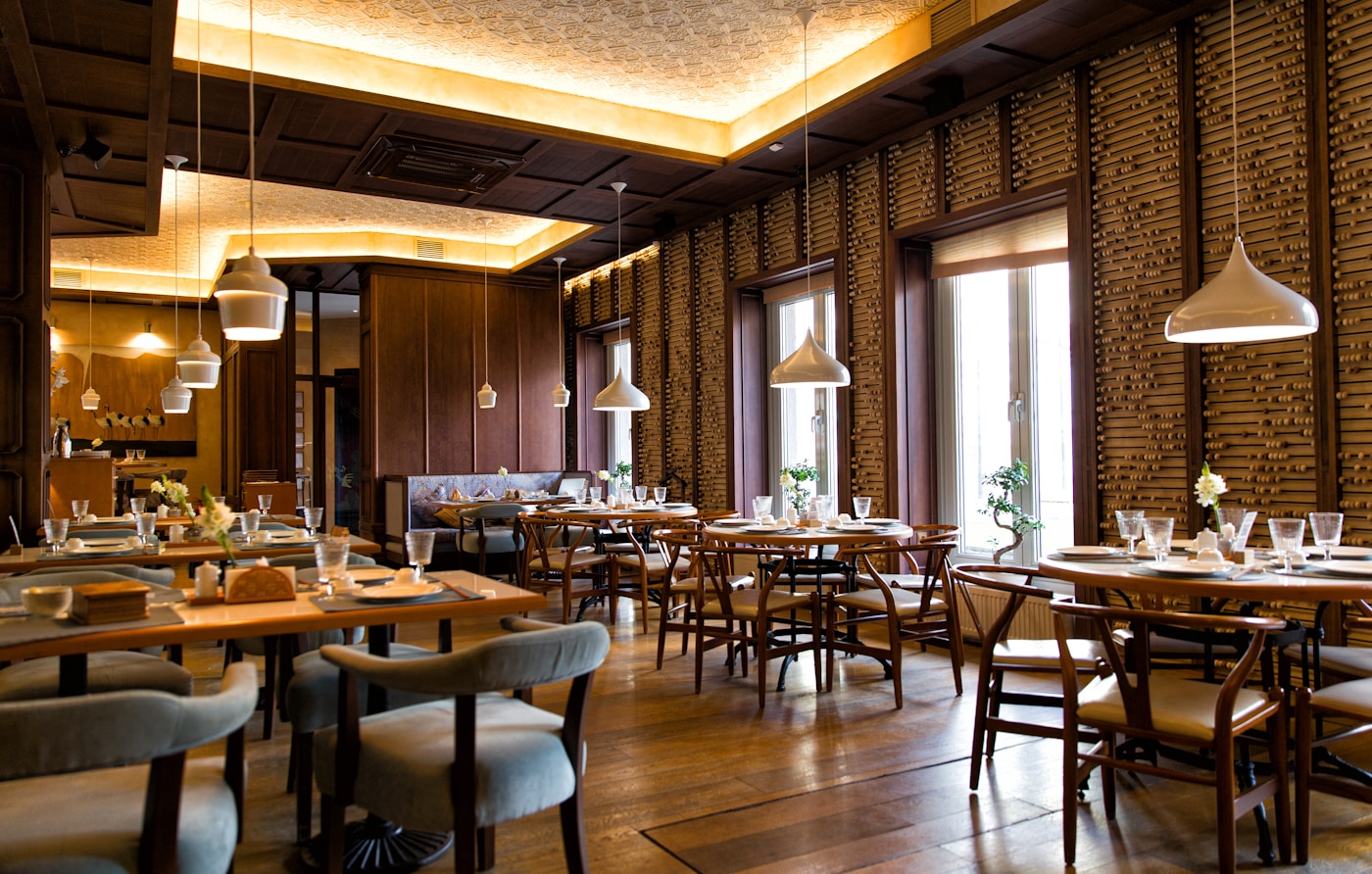 Warmly lit restaurant with thoughtfully set tables, wood finishes and pendant lights